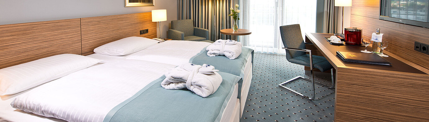Superior Zimmer im Maritim Darmstadt mit stilvollem Design, Schreibtisch, gemütlicher Sitzecke und Doppelbett mit Bademänteln