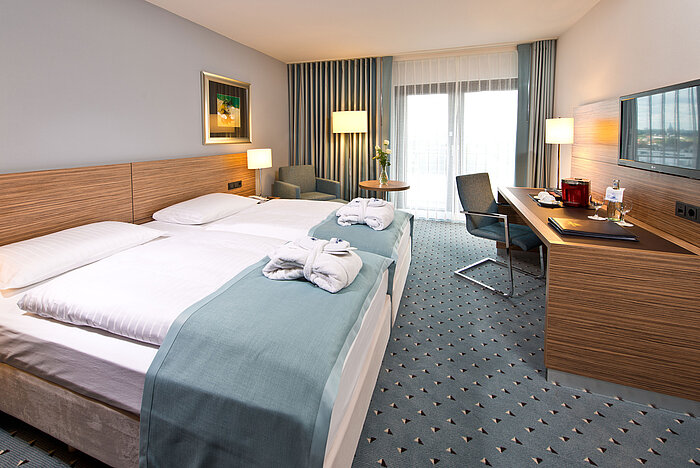 Superior Zimmer im Maritim Darmstadt mit stilvollem Design, Schreibtisch, gemütlicher Sitzecke und Doppelbett mit Bademänteln