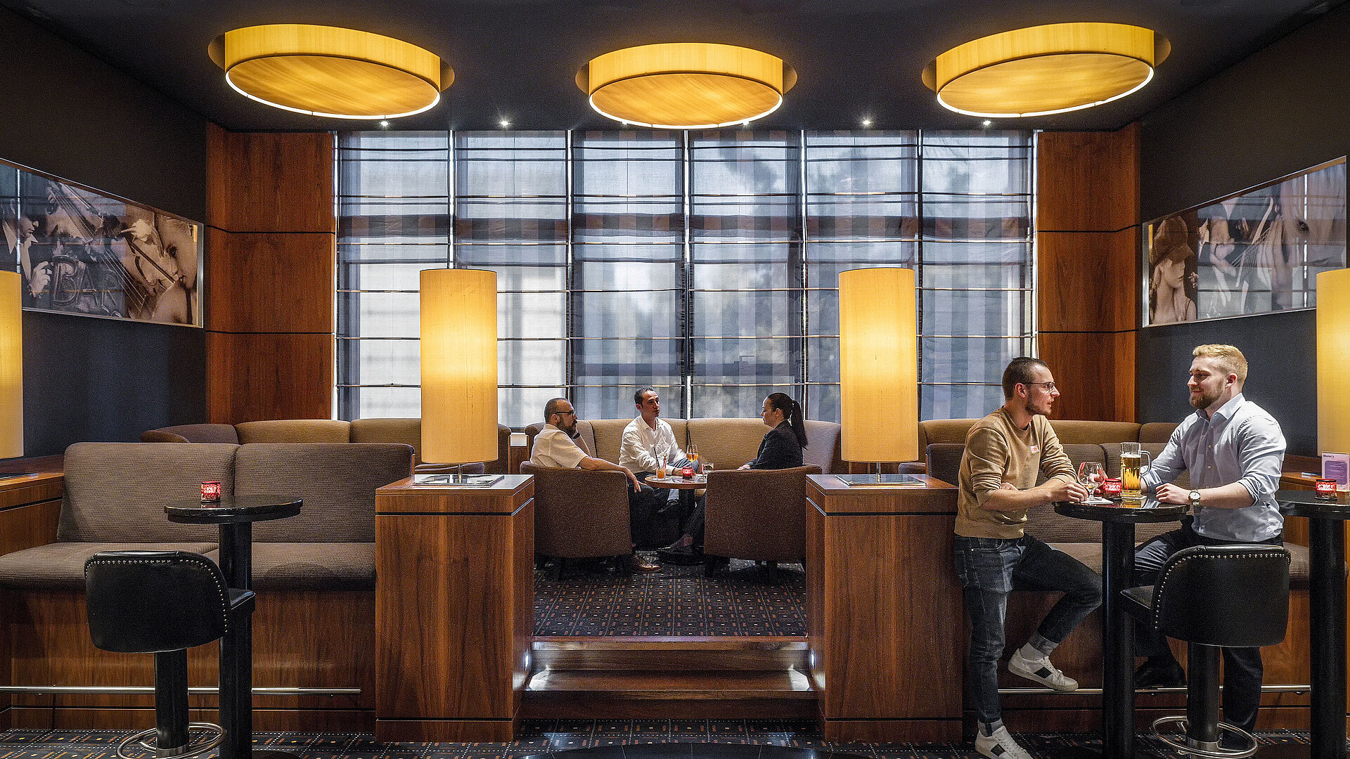 Gemütliche Sitzbereiche in der Hotelbar des Maritim Hotel Düsseldorf mit moderner Beleuchtung und Gästen im Gespräch.