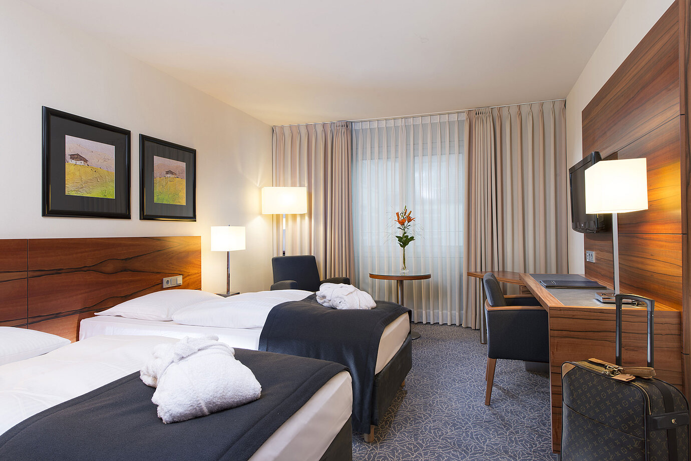 Komfortables Zweibettzimmer im Maritim Hotel München. Mit getrennten Betten, Schreibtisch, TV und Sitzbereich am Fenster. 