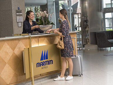 Freundlicher Empfang an der Rezeption des Maritim proArte Hotel Berlin mit lächelnder Mitarbeiterin beim Check-in.