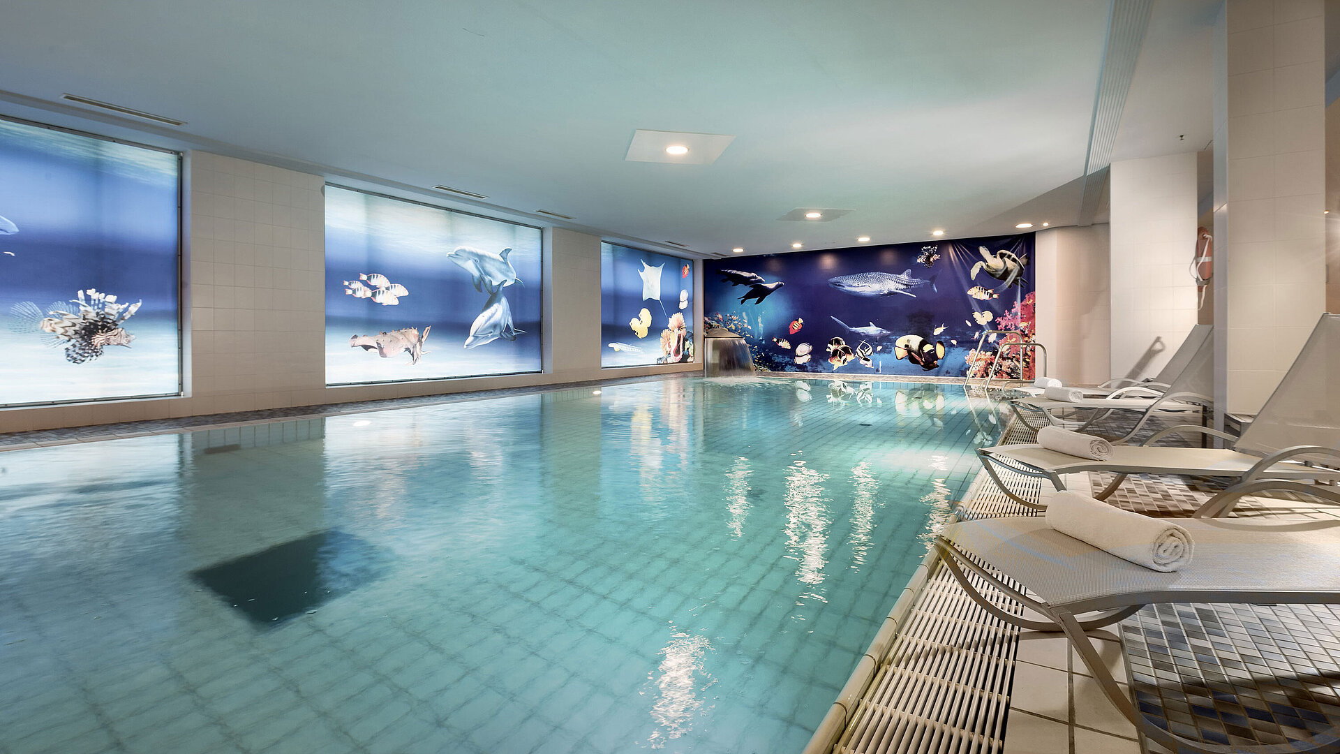 Innenpool im Maritim proArte Hotel Berlin mit Liegen und beeindruckender Unterwasserwelt-Dekoration an den Wänden
