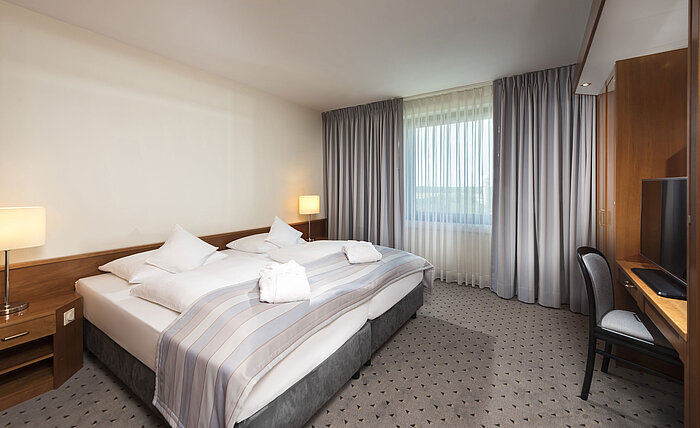 Junior Suite mit gemütlichem Doppelbett, TV, Schreibtisch und großen Fenstern im Maritim Hotel Hannover.