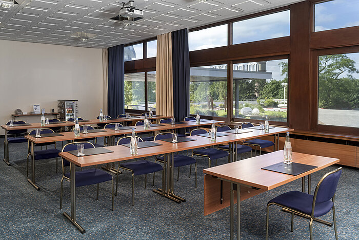 Seminarraum mit Reihenbestuhlung, Teppichboden und großen Fenstern im Maritim Hotel Travemünde