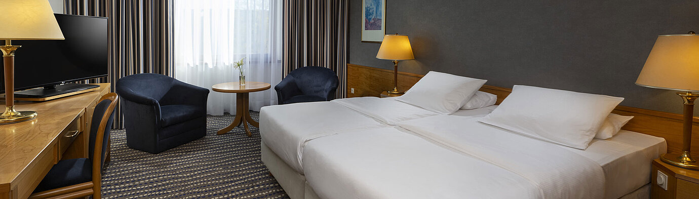 Hotelzimmer mit Doppelbett, TV, Schreibtisch und gemütlicher Sitzecke, ideal für Erholung und Komfort