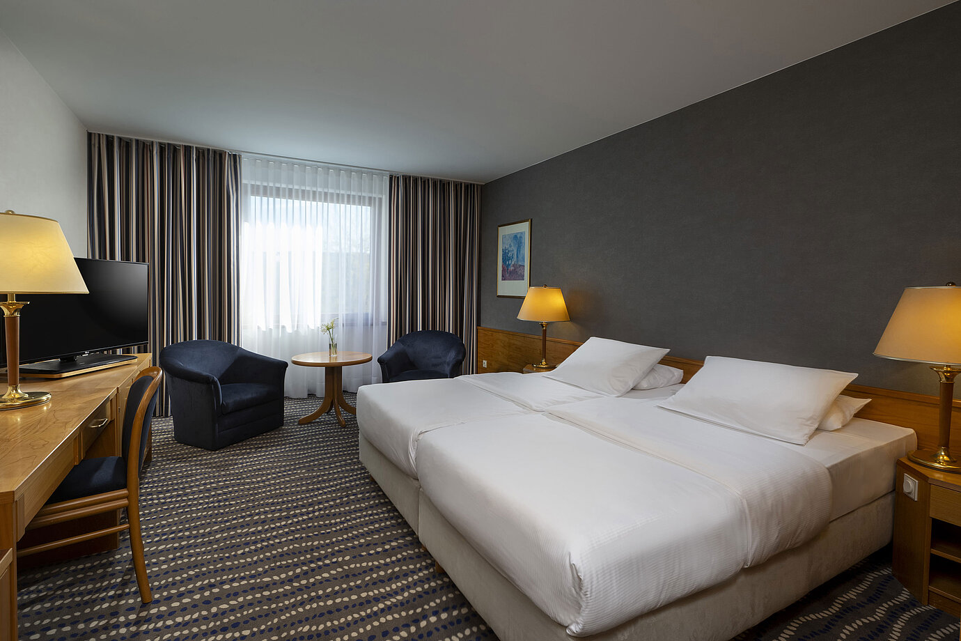 Hotelzimmer mit Doppelbett, TV, Schreibtisch und gemütlicher Sitzecke, ideal für Erholung und Komfort
