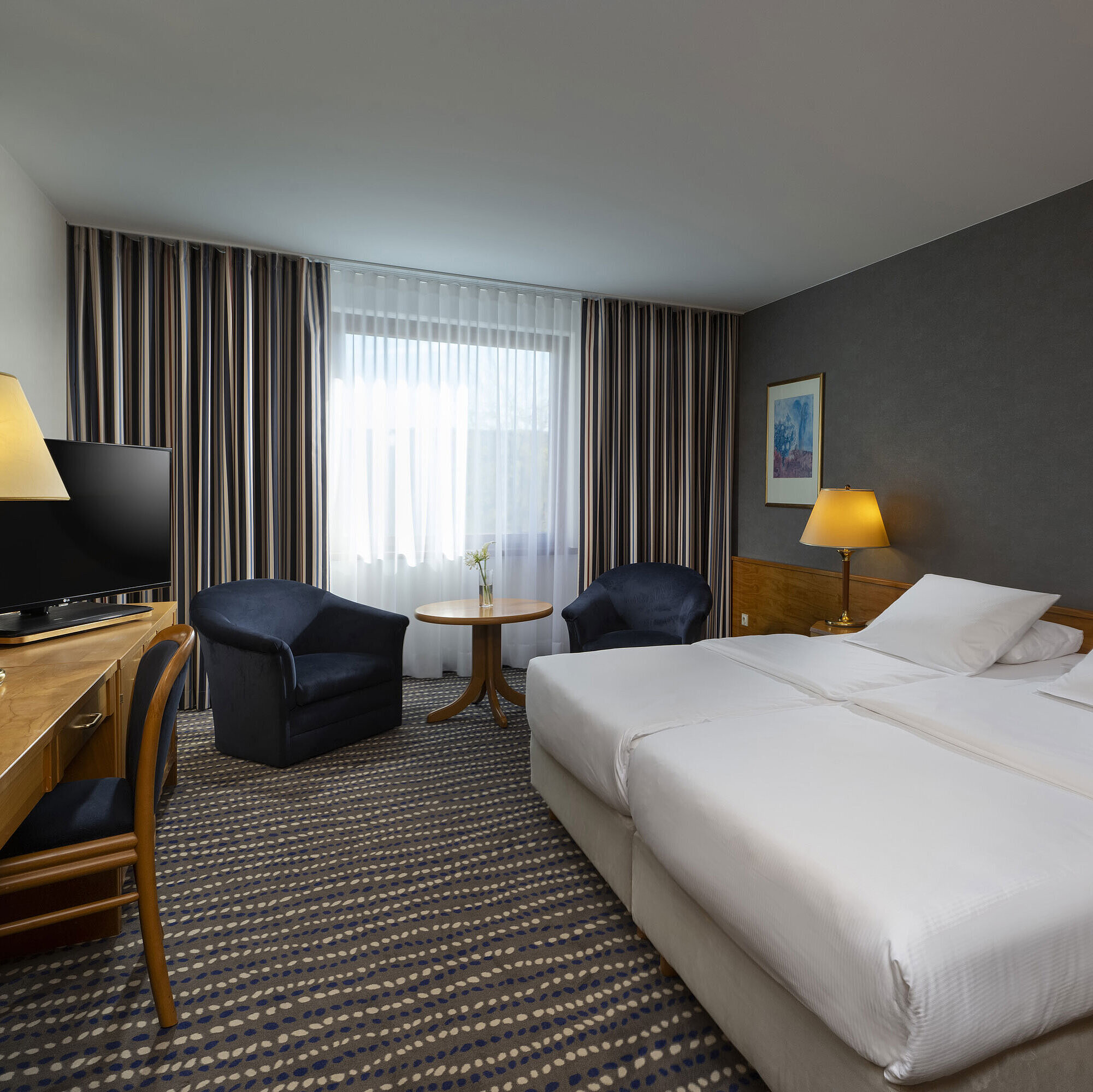 Hotelzimmer mit Doppelbett, TV, Schreibtisch und gemütlicher Sitzecke, ideal für Erholung und Komfort