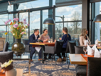 Gäste genießen Speisen im Restaurant des Maritim Hotel Dresden mit Blick nach draußen.