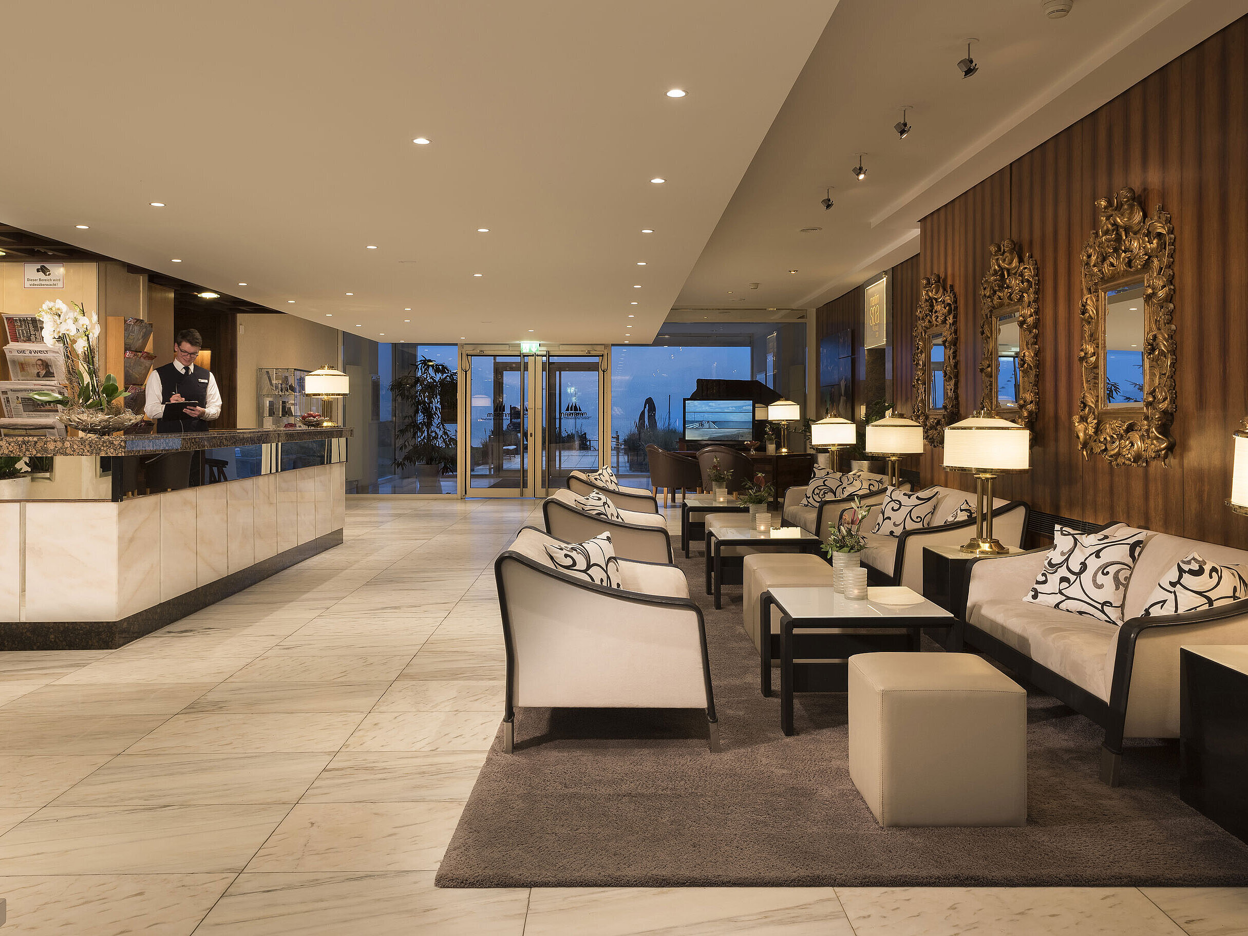 Rezeption und Lobby mit Sitzbereich im Maritim Seehotel Timmendorfer Strand bei Abendbeleuchtung.
