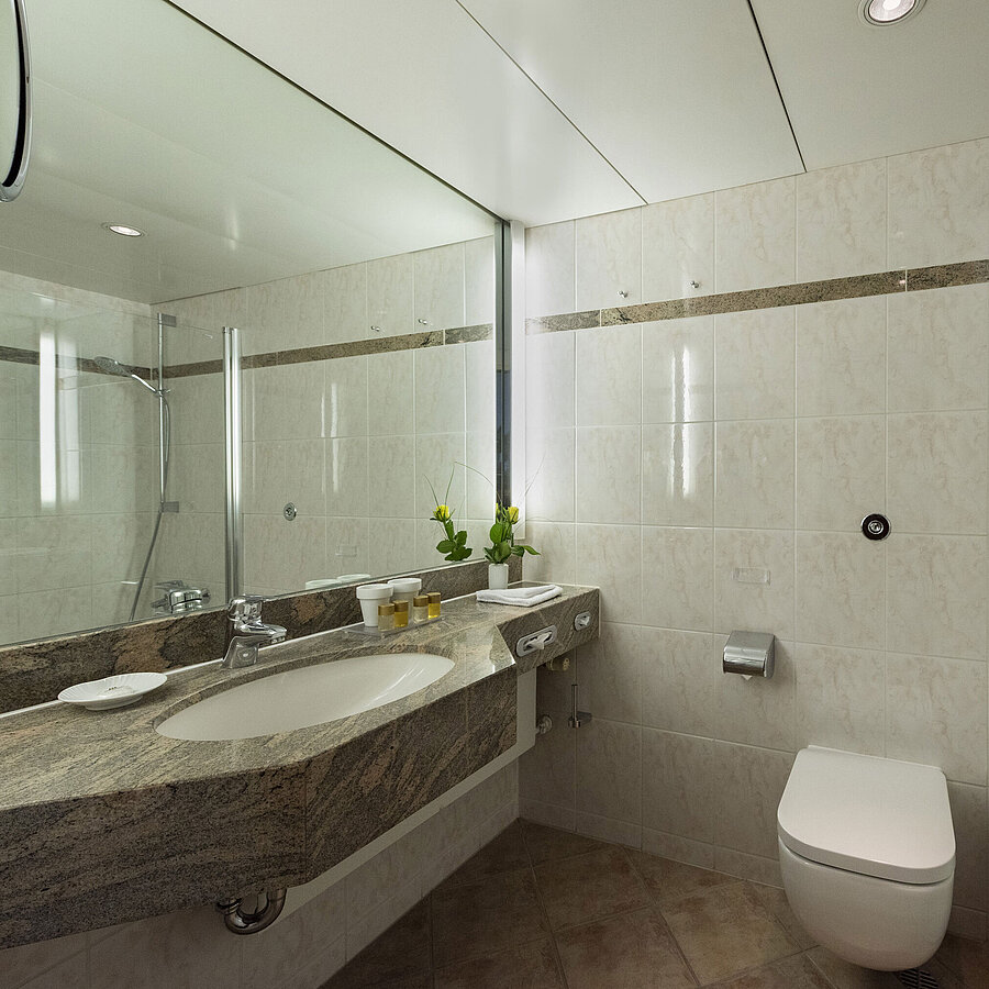 Helles Badezimmer im Maritim Hotel Travemünde mit Granitwaschtisch, Spiegel und Dusche