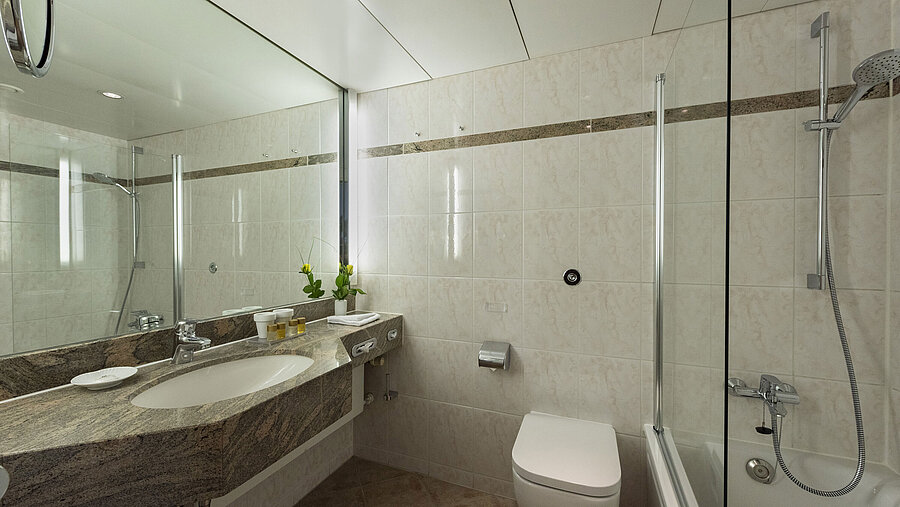 Helles Badezimmer im Maritim Hotel Travemünde mit Granitwaschtisch, Spiegel und Dusche