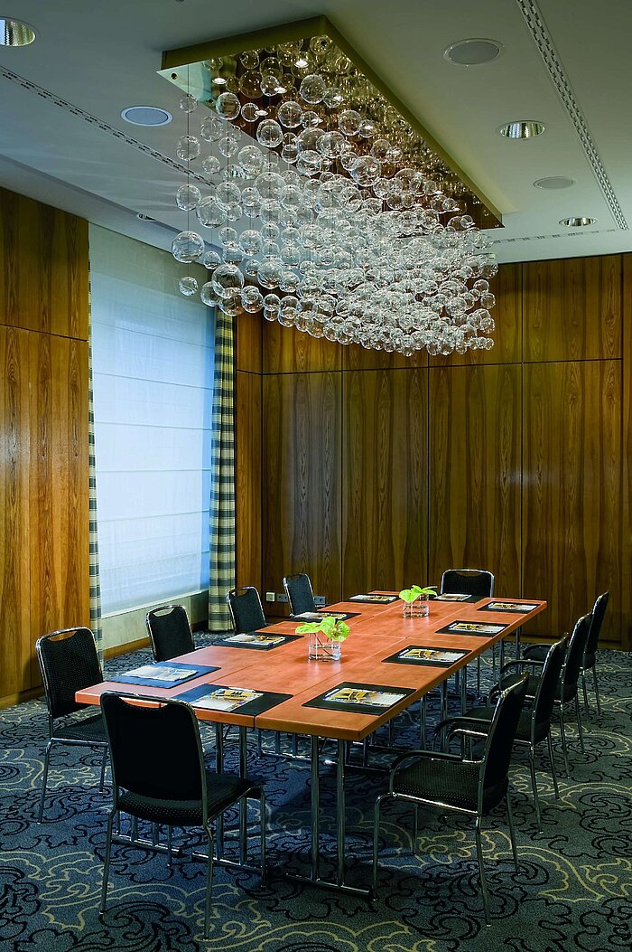 Exklusiver Meetingraum im Maritim Hotel Düsseldorf mit elegantem Tisch, moderner Ausstattung und einzigartigem Kronleuchter.