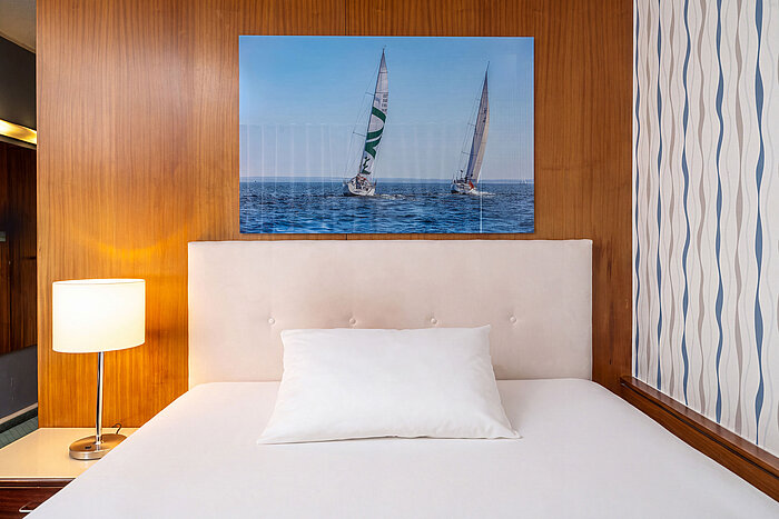 Queensize-Bett im Classic Queen Zimmer mit Nachttischlampe und maritimem Wandbild