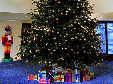 Festlicher Weihnachtsbaum im Foyer mit Geschenken.