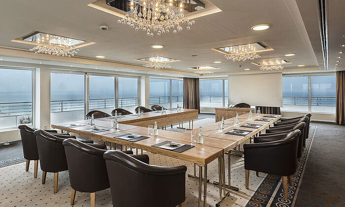 Salon Hamburg im Maritim Seehotel Timmendorfer Strand, Tagungsraum mit Meerblick, L-förmiger Tisch und eleganter Beleuchtung.