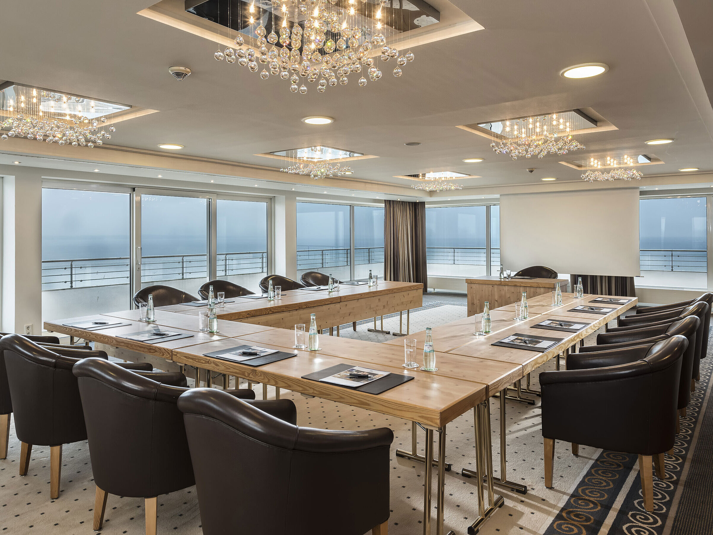 Salon Hamburg im Maritim Seehotel Timmendorfer Strand, Tagungsraum mit Meerblick, L-förmiger Tisch und eleganter Beleuchtung.