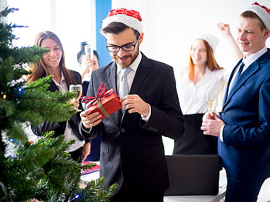 Kollegen beschenken sich bei einer Weihnachtsfeier im Hotel