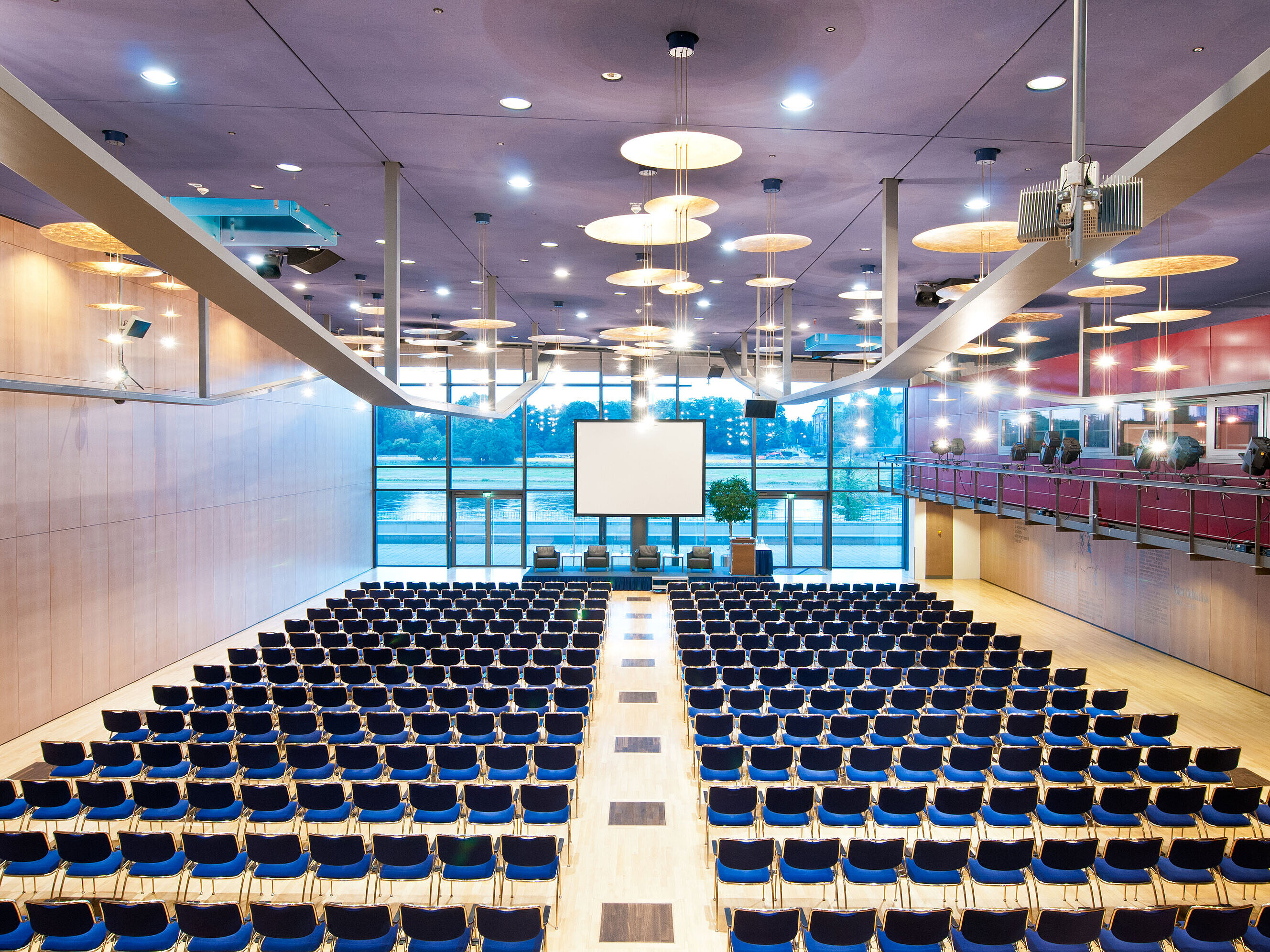 Großer Konferenzsaal im Maritim Hotel Dresden mit Reihen blauer Stühle und Blick auf die Elbe.