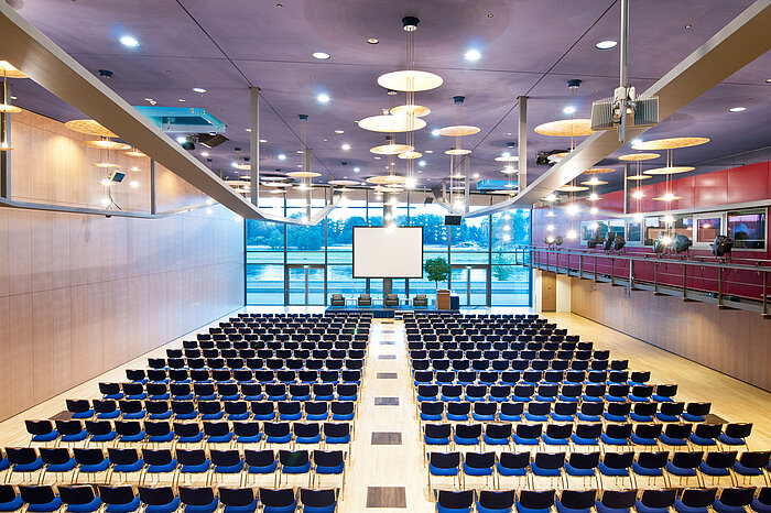 Großer Konferenzsaal im Maritim Hotel Dresden mit Reihen blauer Stühle und Blick auf die Elbe.