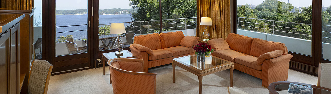 Heller Wohnbereich der Präsidentensuite im Maritim Hotel Kiel mit Panoramablick auf die Ostsee und stilvollen Möbeln.