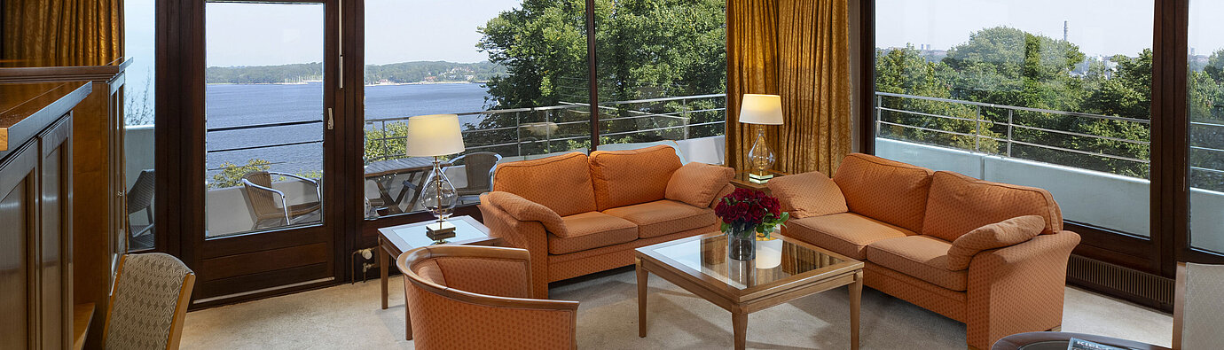 Heller Wohnbereich der Präsidentensuite im Maritim Hotel Kiel mit Panoramablick auf die Ostsee und stilvollen Möbeln.