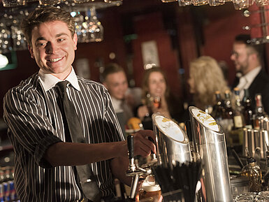 Freundlicher Barkeeper serviert Drinks in der stilvollen Bar des Maritim Hotel Frankfurt.