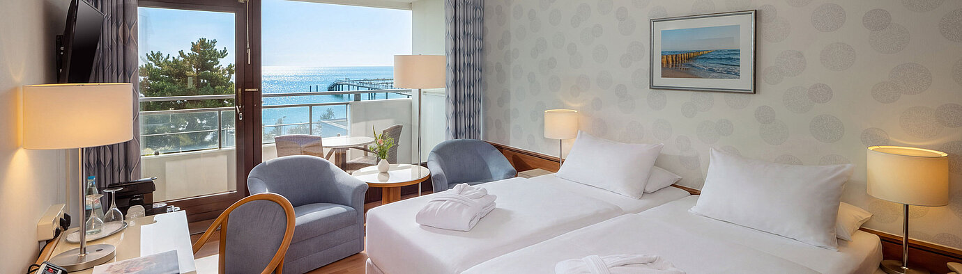 Superior Zimmer mit Doppelbett, Schreibtisch, Sitzecke und Balkon mit Blick auf die Ostsee