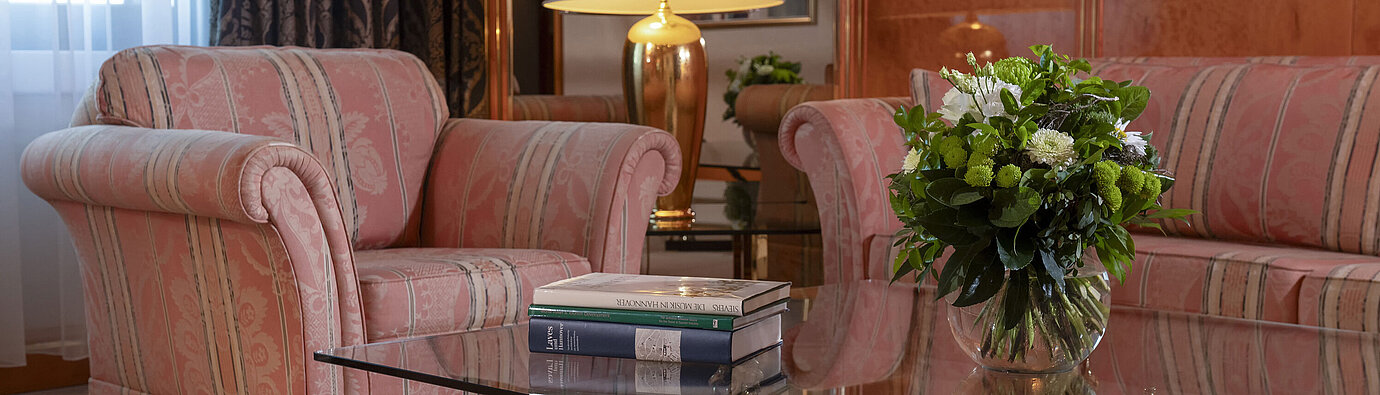 Stilvolles Wohnzimmer im Maritim Hotel Hannover mit eleganter Sitzgruppe und Glas-Couchtisch.