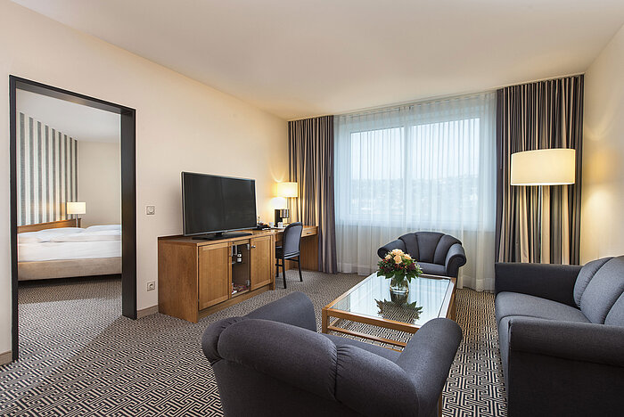 Großzügiger Wohnbereich mit Sofa, Sessel, TV und Schreibtisch in der Suite des Maritim Hotel Stuttgart