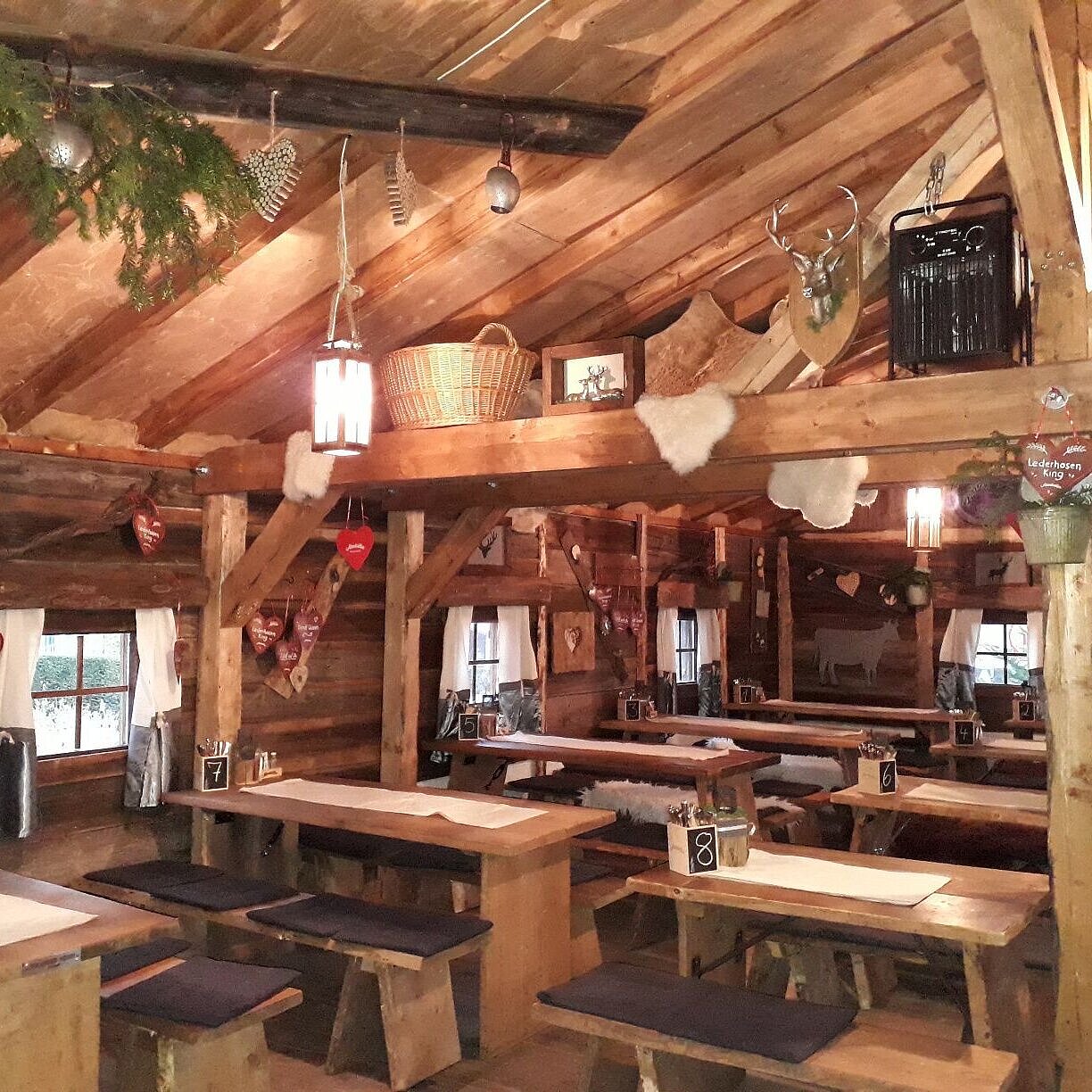 Gemütlicher Gastraum mit Holztischen und Almhütten-Deko in der Maritim Alm beim Maritim Hotel Stuttgart