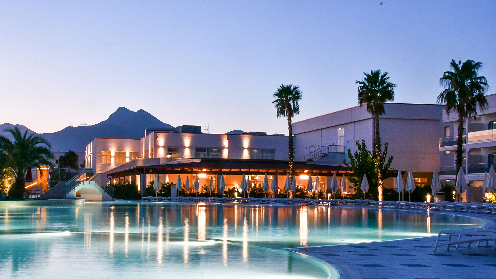 Poolbeleuchtung am Abend im Maritim Resort Calabria mit Palmen und Gebirgskulisse