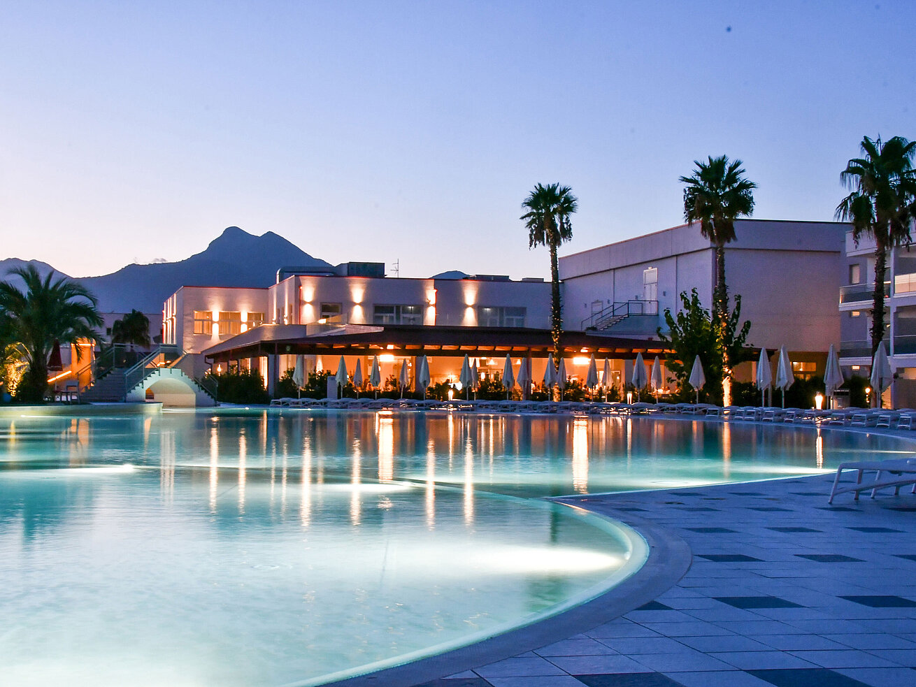 Poolbeleuchtung am Abend im Maritim Resort Calabria mit Palmen und Gebirgskulisse