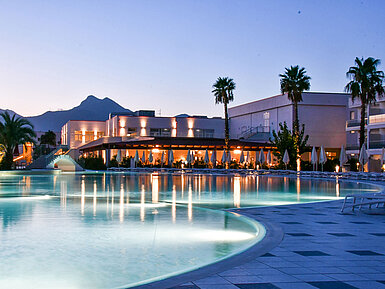 Poolbeleuchtung am Abend im Maritim Resort Calabria mit Palmen und Gebirgskulisse