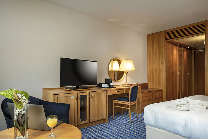 Schreibtisch mit Fernseher und Lampe in einem Superior-Zimmer mit Holzeinrichtung und blauen Akzenten.