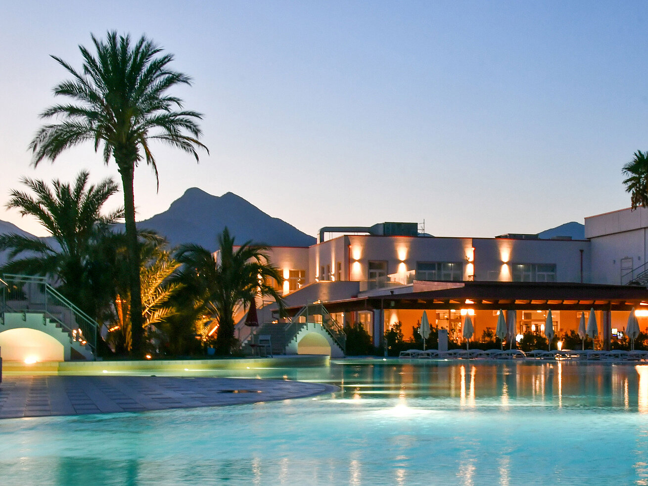Poolbeleuchtung am Abend im Maritim Resort Calabria mit Palmen und Gebirgskulisse