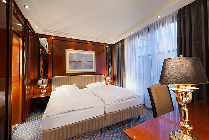 Elegante Suite im Maritim Hotel Fulda mit luxuriösem Doppelbett, stilvollen Holzelementen und gemütlicher Beleuchtung.