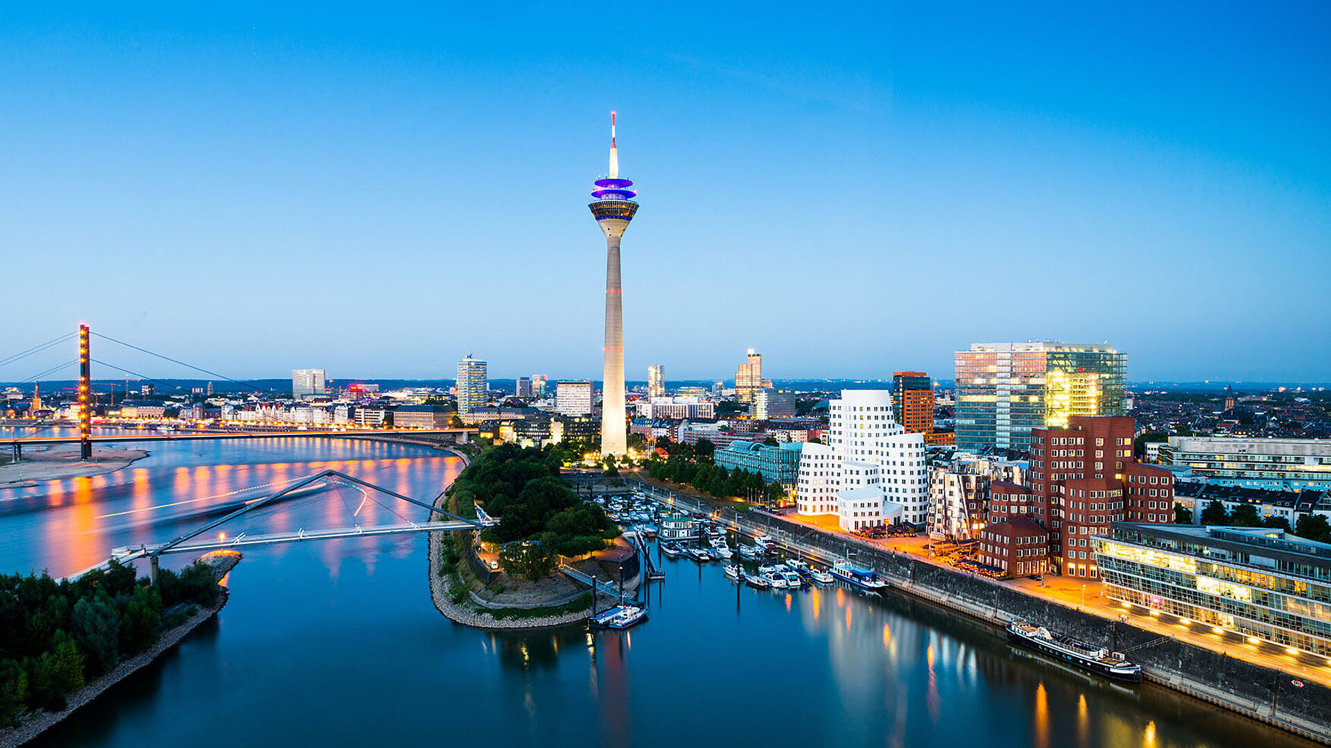 Düsseldorf Skyline mit Rheinturm, Rheinpromenade und moderner Architektur bei Abenddämmerung.