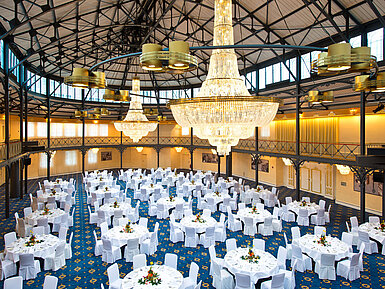 Großer Bankettsaal mit runden, festlich gedeckten Tischen und beeindruckenden Kronleuchtern im Maritim Hotel Stuttgart