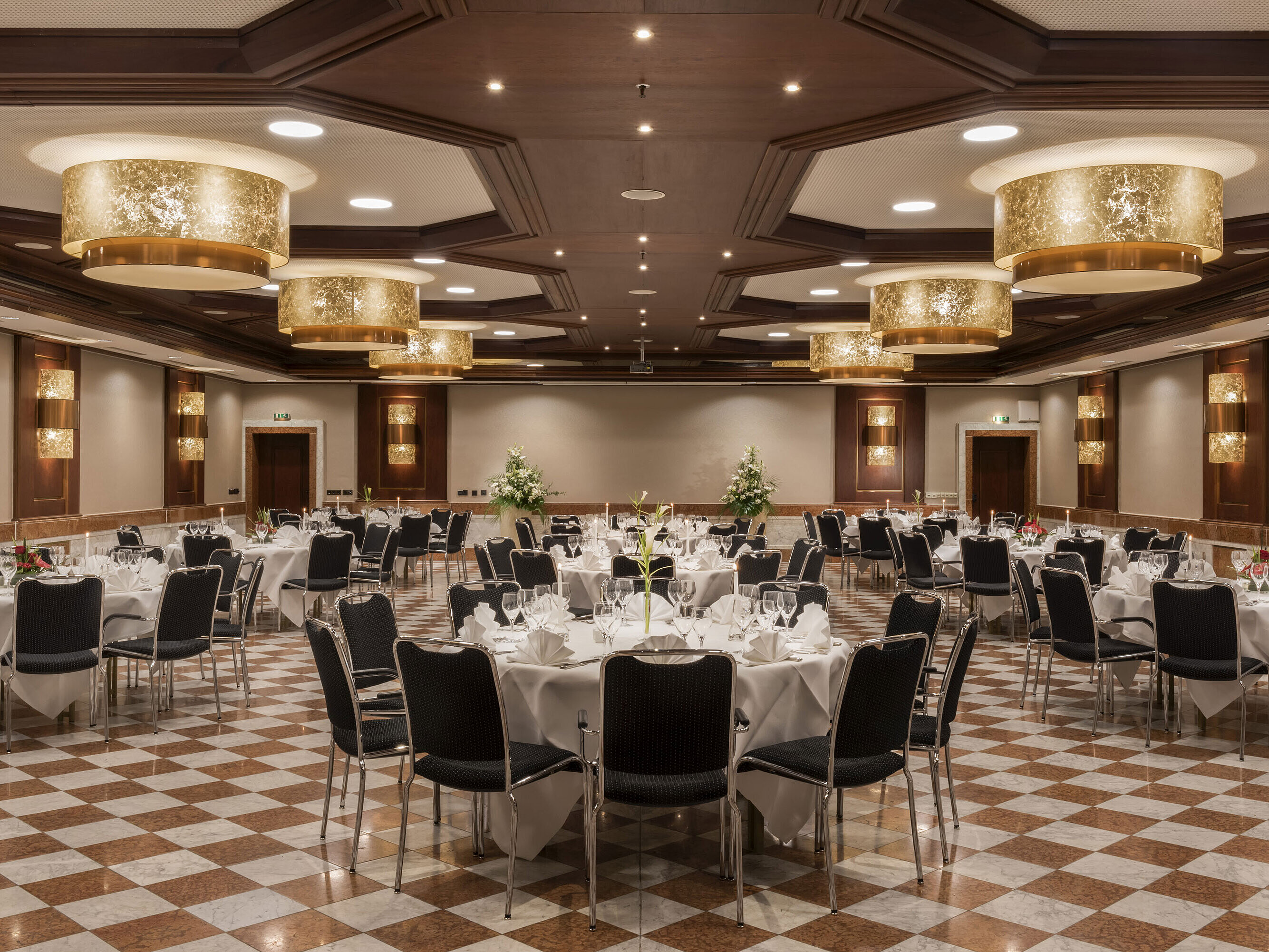 Eleganter Festsaal im Maritim Hotel Königswinter mit runden Tischen, stilvoller Dekoration und Kronleuchtern.