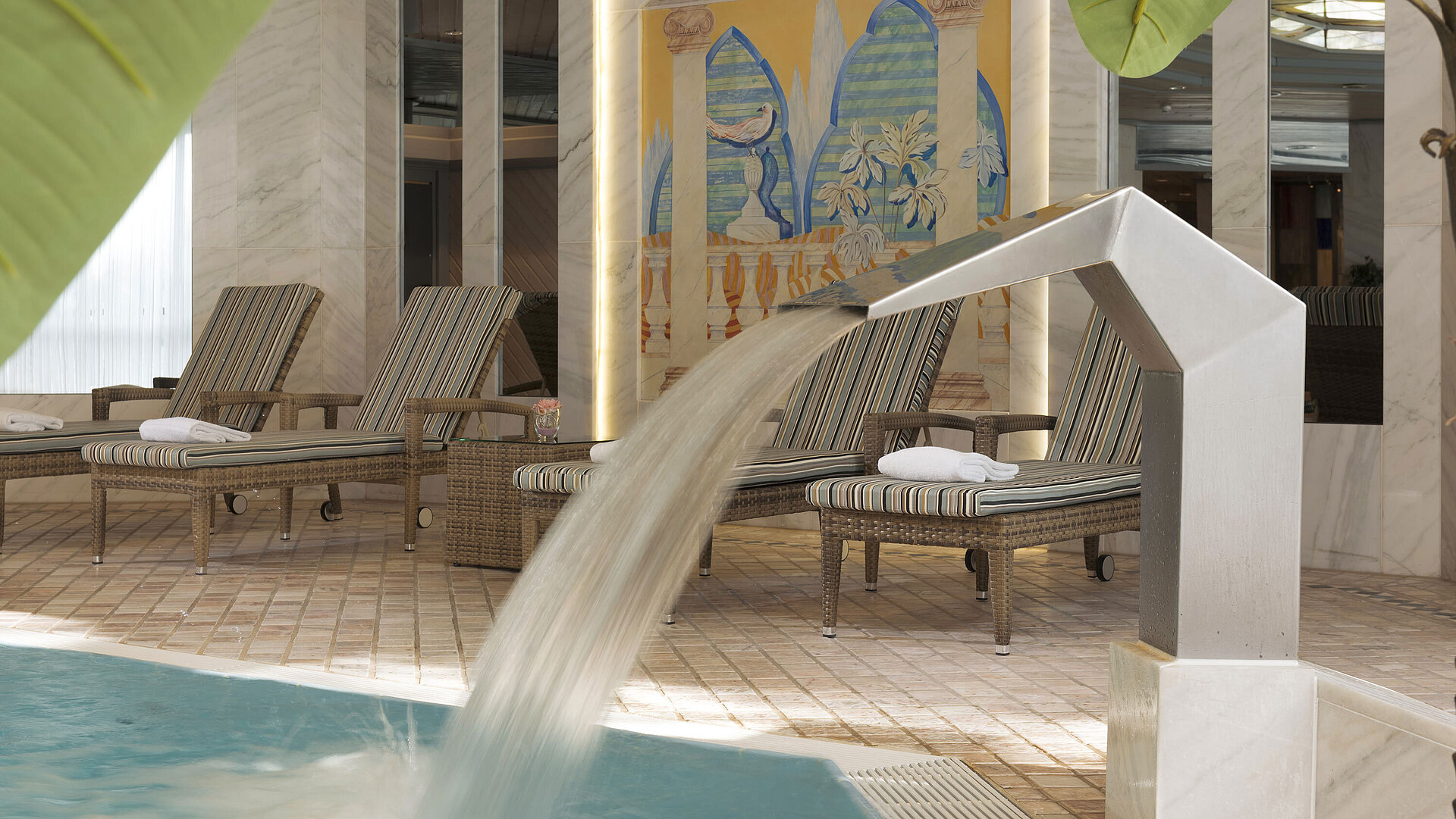 Moderner Innenpool mit Wasserfall und Relaxliegen im Maritim Hotel Ulm für deine erholsame Auszeit.