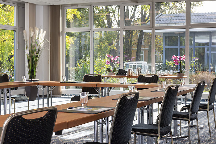 Heller Tagungsraum mit großen Fenstern und Blick ins Grüne im Maritim Hotel Königswinter.