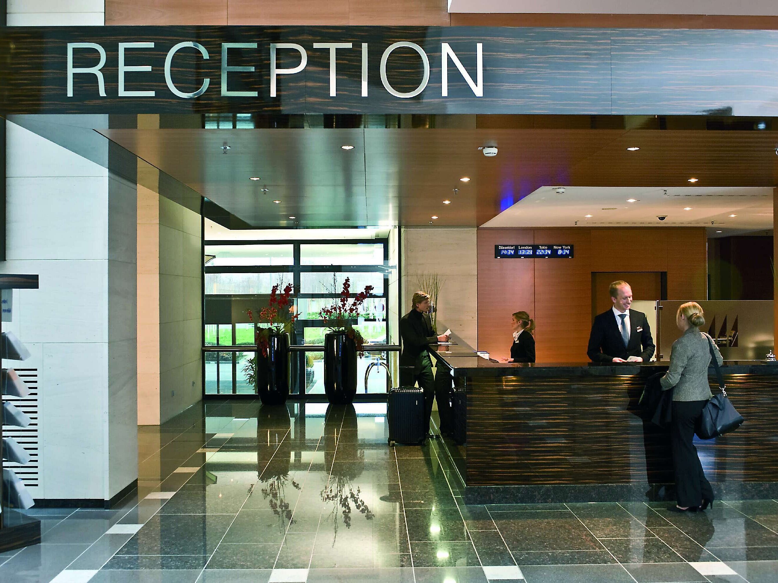 Rezeption im Maritim Hotel Düsseldorf mit freundlichem Empfangspersonal und modernem Design, ideal für Check-ins und Gästeservice.