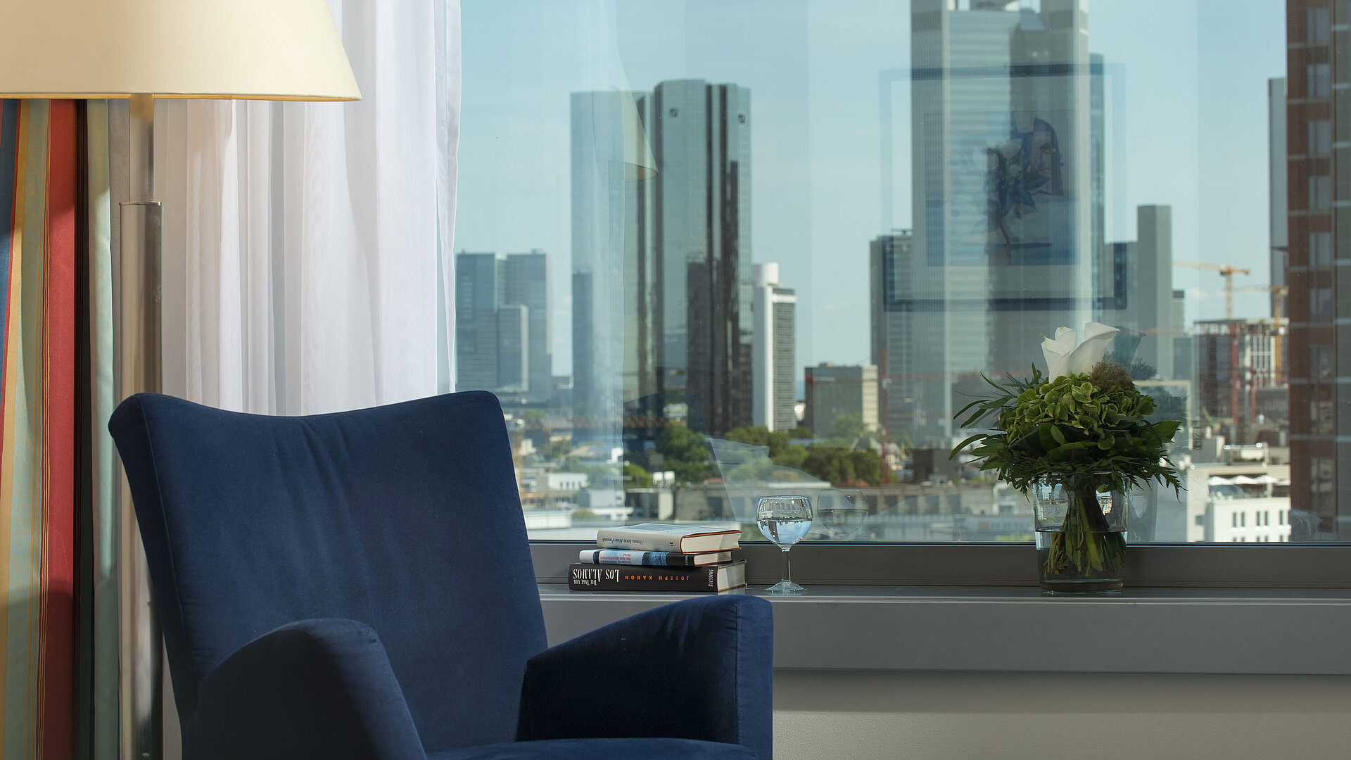 Ausblick aus einer Suite im Maritim Hotel Frankfurt mit Skyline-Blick, blauem Sessel und dekorativem Blumenarrangement.