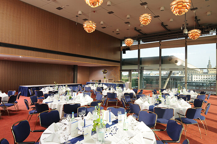  Eleganter Veranstaltungsraum im Maritim Hotel Dresden mit festlich gedeckten Tischen und Blick auf die Stadt.