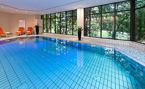 Moderner Innenpool im Maritim Hotel Bad Homburg mit stilvoller Wellenwand und bequemen Liegen.