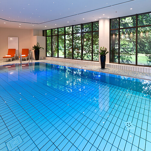 Moderner Innenpool im Maritim Hotel Bad Homburg mit stilvoller Wellenwand und bequemen Liegen.
