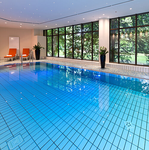 Moderner Innenpool im Maritim Hotel Bad Homburg mit stilvoller Wellenwand und bequemen Liegen.
