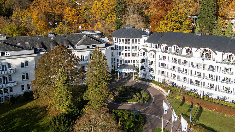 Außenansicht des Maritim Hotel Bad Wildungen mit Park, Bäumen und zentralem Eingangsbereich im herbstlichen Umfeld.