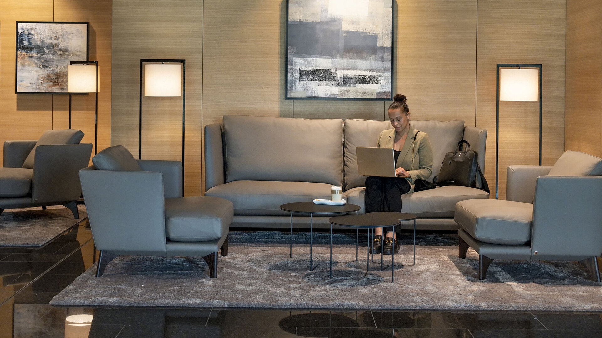 Eine Frau arbeitet mit ihrem Laptop in der stilvollen Lounge des Maritim Hotel Ingolstadt.