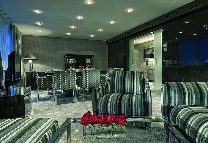 Wohnzimmer der Master Suite im Maritim Düsseldorf mit modernen Sitzmöbeln, stilvollem Esstisch und gemütlicher Beleuchtung.